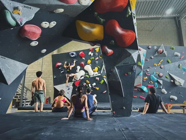 Pessoas escalando e descansando juntas no ginásio da Geometrik